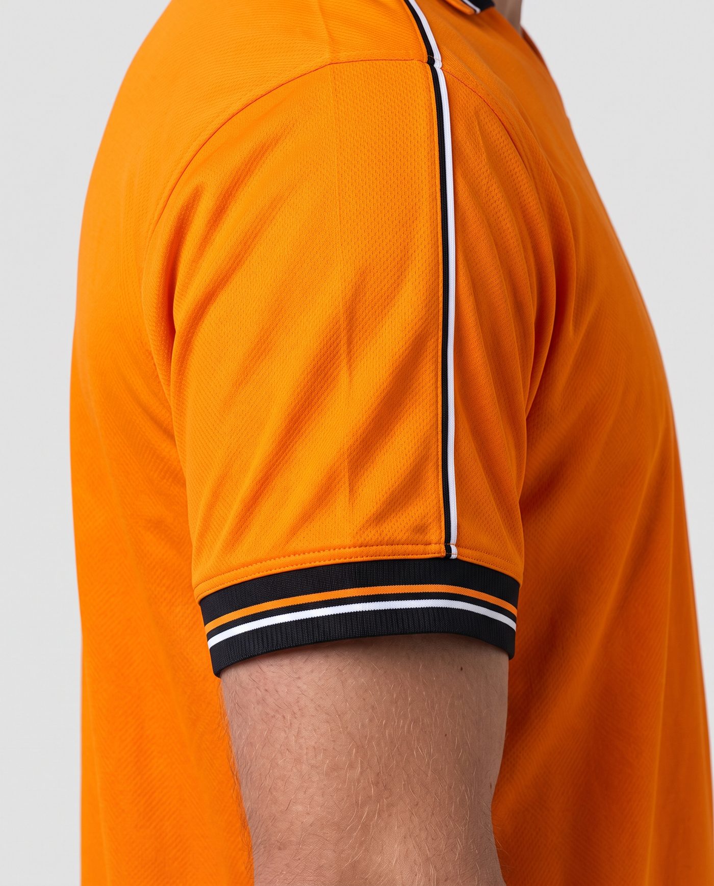Close-up of the left sleeve, orange with the black and white piping, of the Mendieta 6 shirt