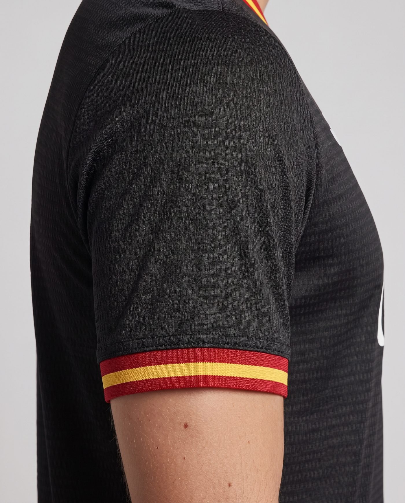 Detalle de la manga izquierda, negra con el puño rojo y amarillo, de la camiseta Pirri 8